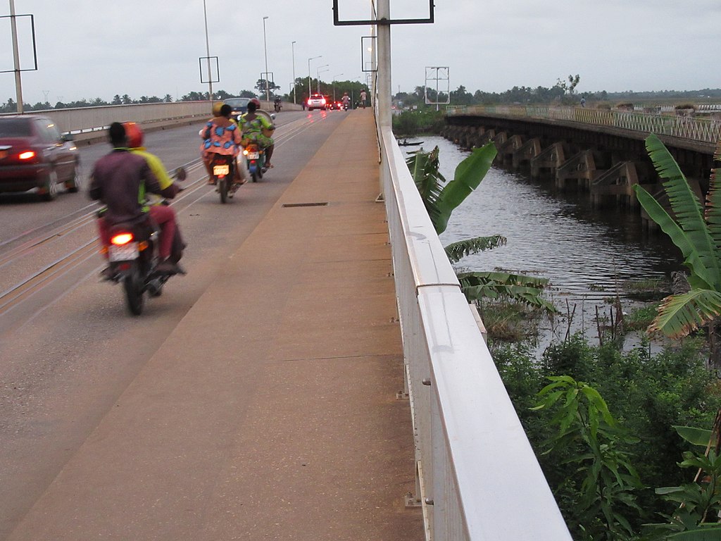 Circulation urbaine animée dans une rue de Porto-Novo au Bénin, incluant des motos-taxis Zémidjans
