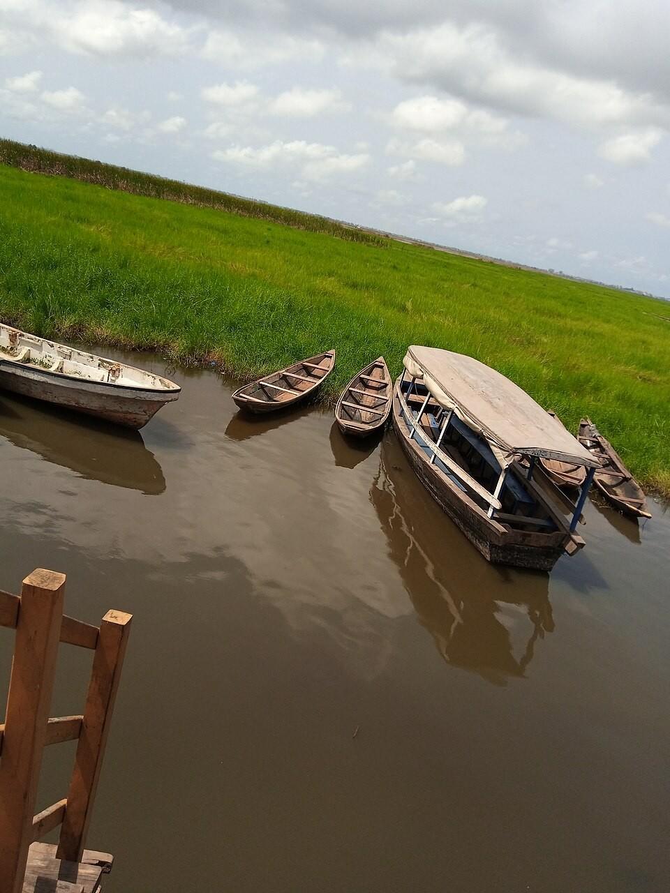 Pirogue navigant sur le lac Nokoué sous la lumière dorée de la saison sèche, condition idéale pour visiter Ganvié au Bénin