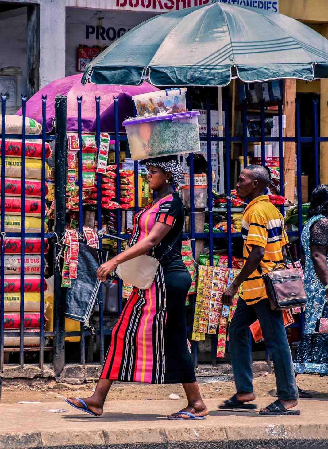 Vendeuse souriante au marché artisanal, présentation de tissus wax et artisanat local béninois