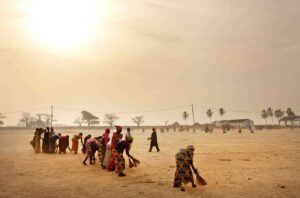 nettoyage des femmes avec des balais africains en fibres au coucher du soleil