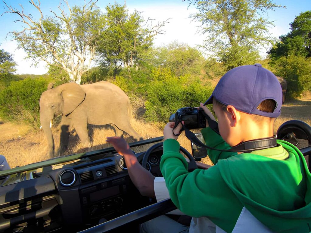 Véhicule de safari traversant la savane du parc national avec une famille à son bord