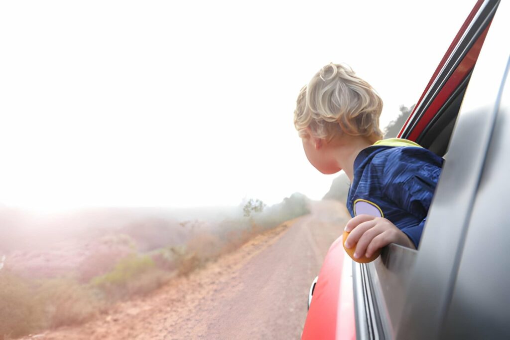 Enfant regardant le paysage béninois depuis la voiture pendant un circuit en famille
