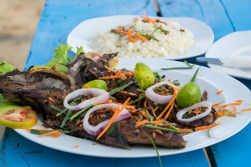 Où manger à Cotonou ? Le guide des meilleurs restaurants 3 Table dressée en bord de plage a Fidjrossè avec poisson grille, illustrant les meilleurs restaurants a Cotonou