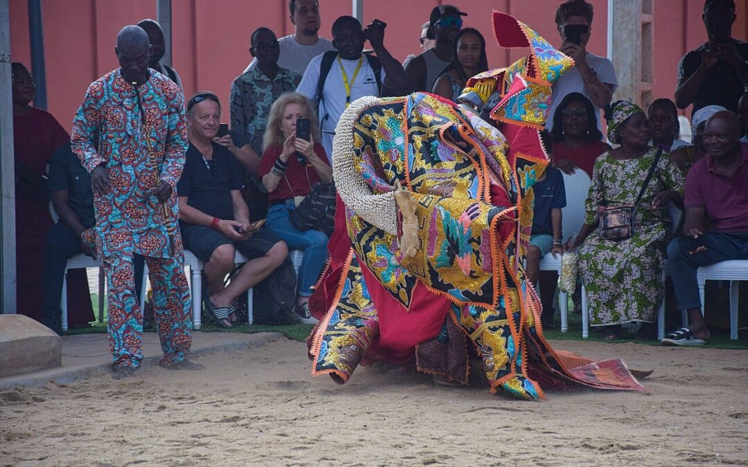 Photographe discret prenant des photos du vaudou lors d'une cérémonie traditionnelle en plein air au Bénin