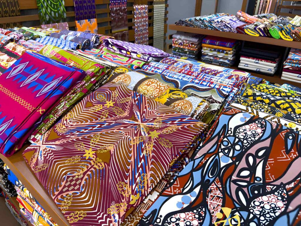 Rouleaux de tissu wax coloré exposés sur un étal du marché Dantokpa à Cotonou