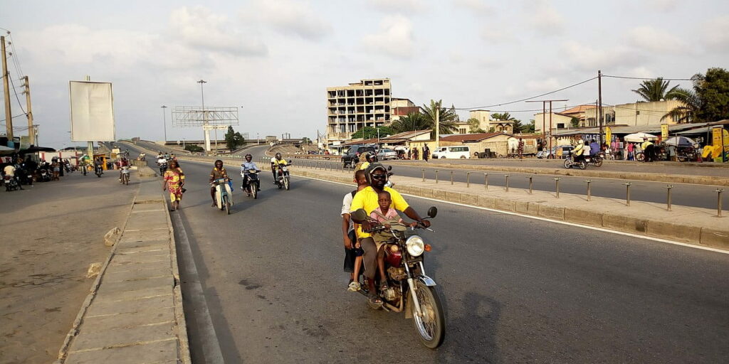 Zémidjans circulant au milieu du trafic dense d'une avenue de Cotonou en journée