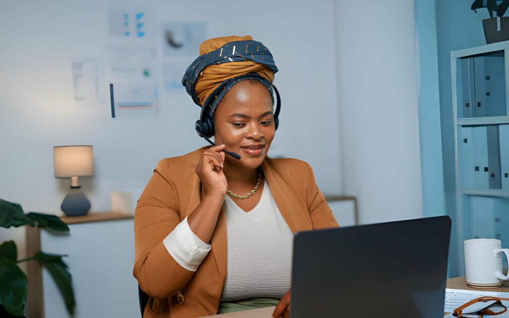 Agences de voyage au Bénin : tout savoir pour organiser votre séjour 2 Conseillère en tenue professionnelle avec casque micro échangeant par appel devant son ordinateur, agence de voyage au Bénin