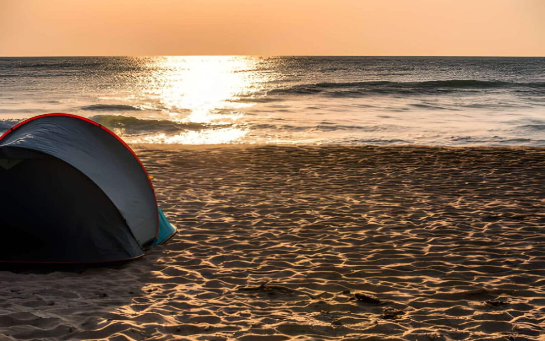 Tente de camping plantée sur une plage du littoral du Bénin au coucher du soleil
