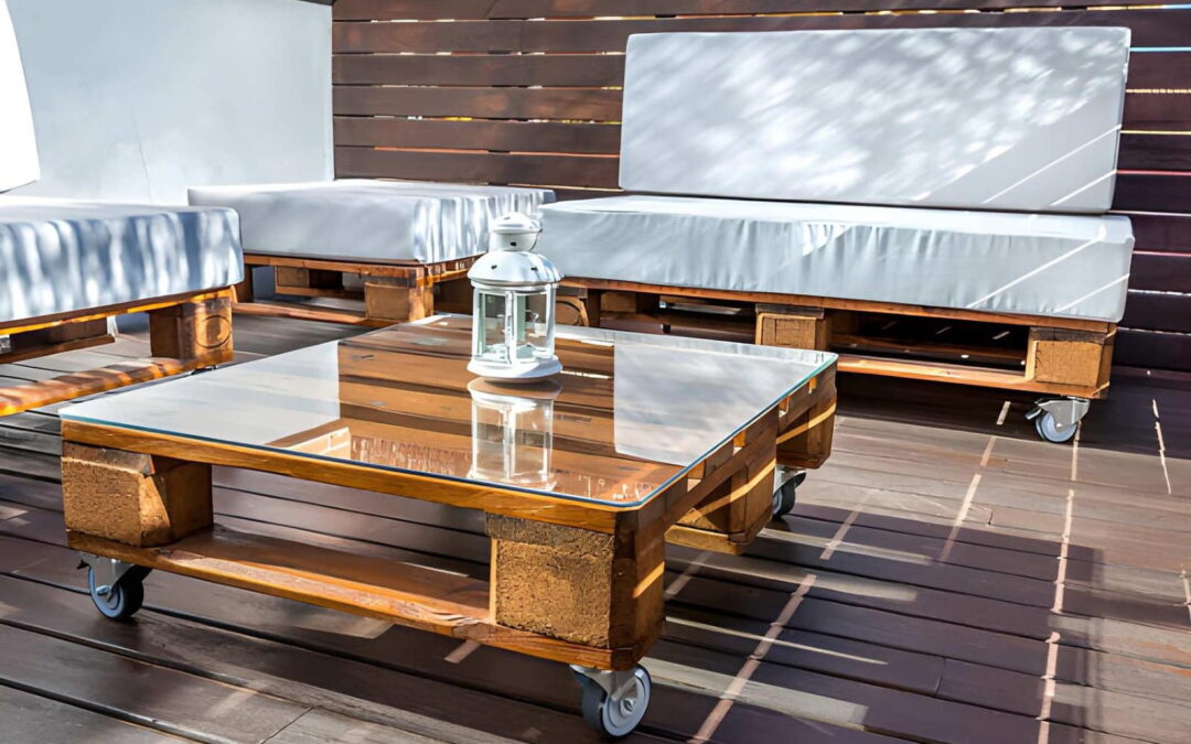 Terrasse de guesthouse à Cotonou avec salon en palettes, table basse à plateau de verre, lanterne et coussins gris sur un sol en bois
