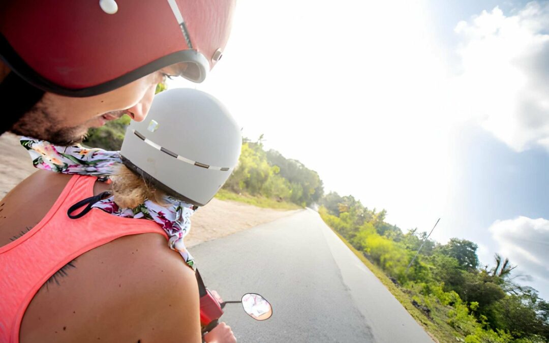 Deux touristes casqués à moto sur une route bordée de végétation tropicale, illustration de la location de moto à Cotonou