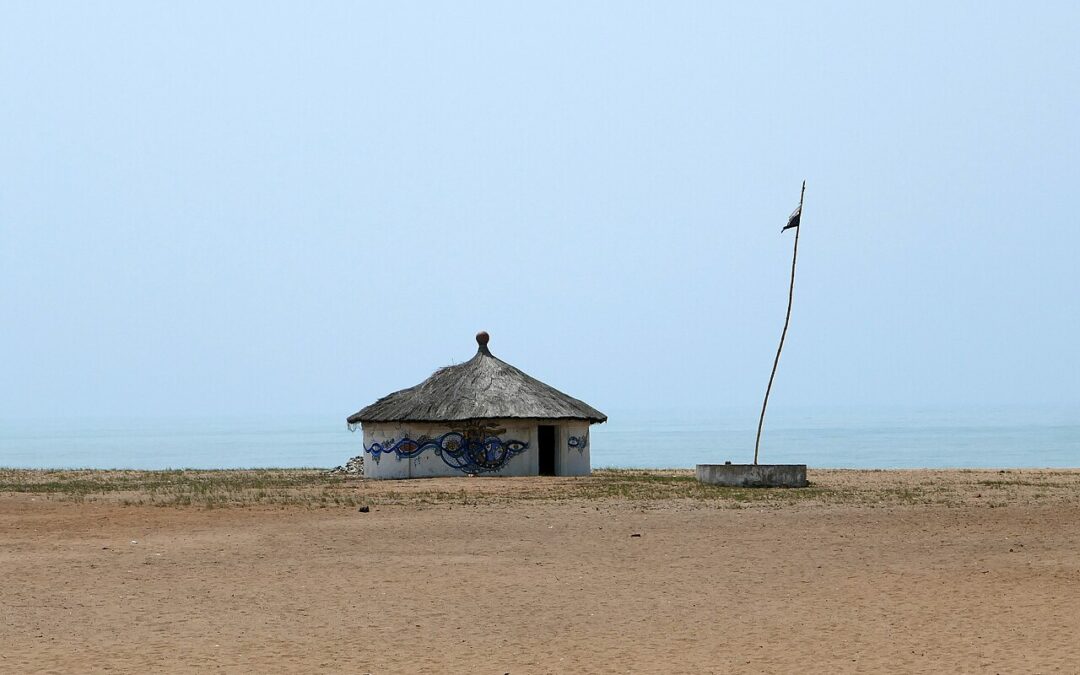 Petit temple de Mami Wata au Bénin, case à toit de chaume peinte d’un motif bleu, sur la plage de ouidah face à l’océan